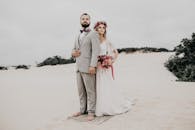 新娘和新郎身着优雅的服装，漫步在浪漫的沙丘上