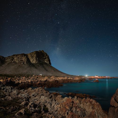 Free A breathtaking view of the starry night sky over rocky shores at Pringle Bay, South Africa. Stock Photo