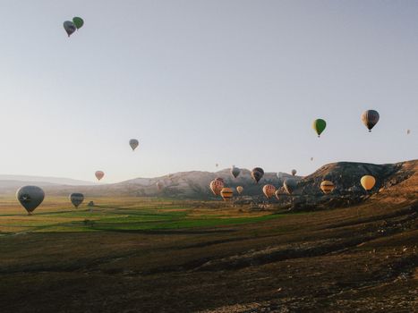 Hot air balloons soar over Cappadocia's unique landscape at sunrise.