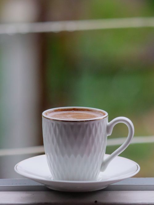 Free A white coffee cup filled with hot beverage sits by a window, offering a cozy and serene ambiance. Stock Photo