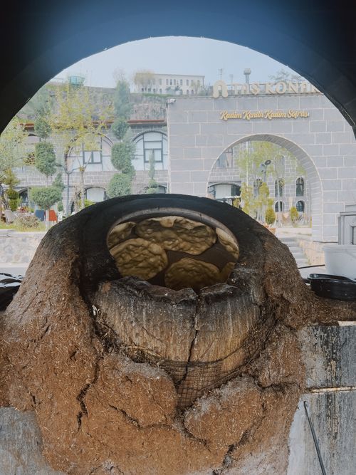 Free A rustic stone oven baking fresh bread outdoors near a historic archway. Stock Photo