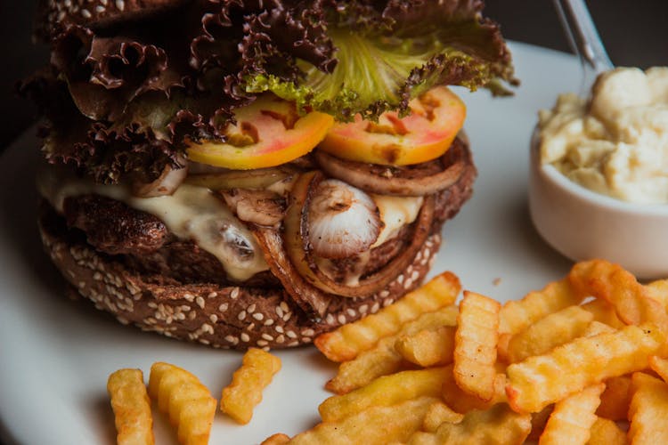 Burger With Sliced Tomato And Lettuce On White Ceramic Plate