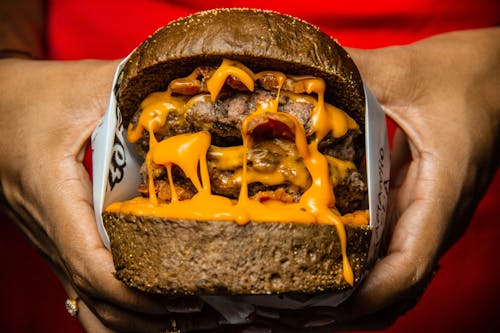 Person holding Burger With Cheese and Bacon