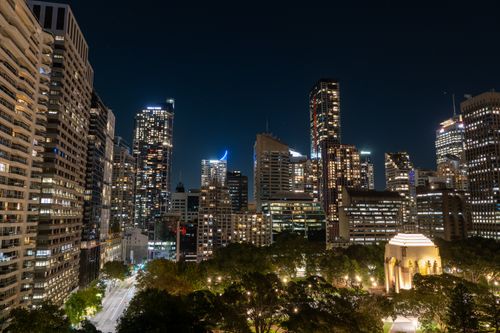 Free Captivating skyline of downtown Sydney at night, featuring illuminated skyscrapers and the iconic ANZAC Memorial. Stock Photo