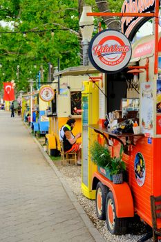 Vibrant street food scene with food trucks and colorful signs in a park setting.