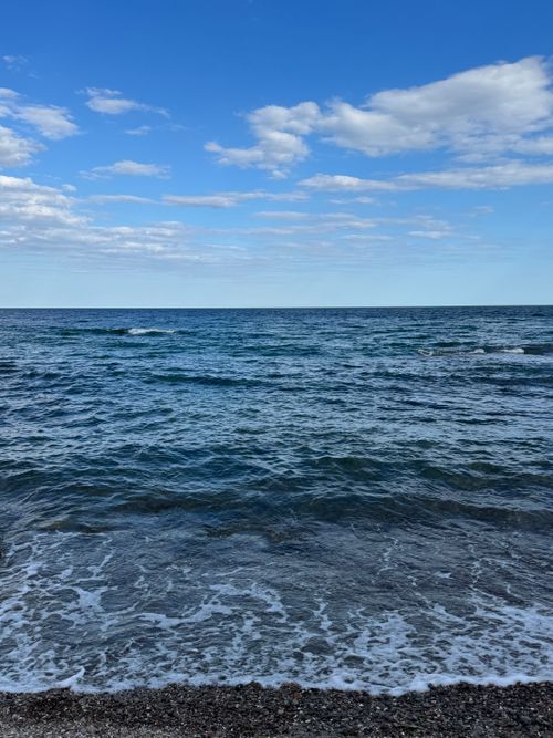 Free Serene view of the Black Sea waves gently lapping the shore under a bright blue sky. Stock Photo