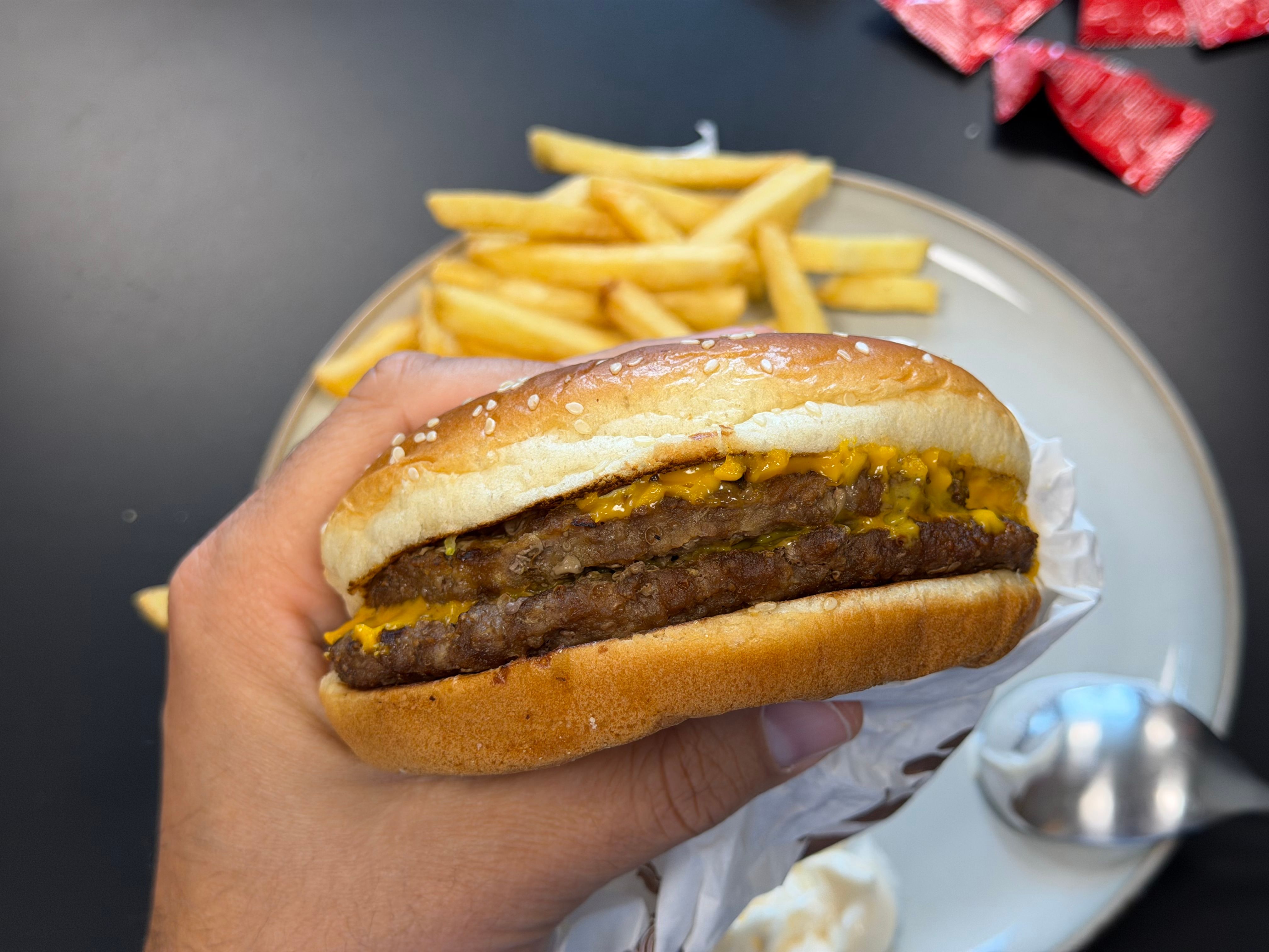 Close-up of burger with multiple patties showing layers of cheese and pickles