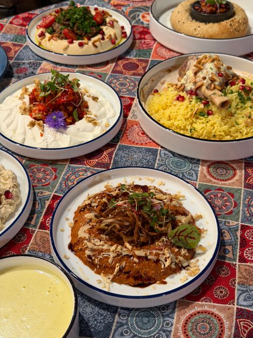 Free Vibrant Middle Eastern dishes on a colorful tablecloth, featuring various meat, rice, and salad items. Stock Photo