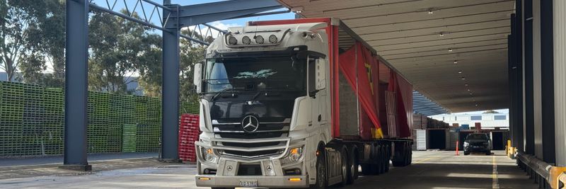 Large truck parked in a loading bay under a roof, ready for industrial transport.