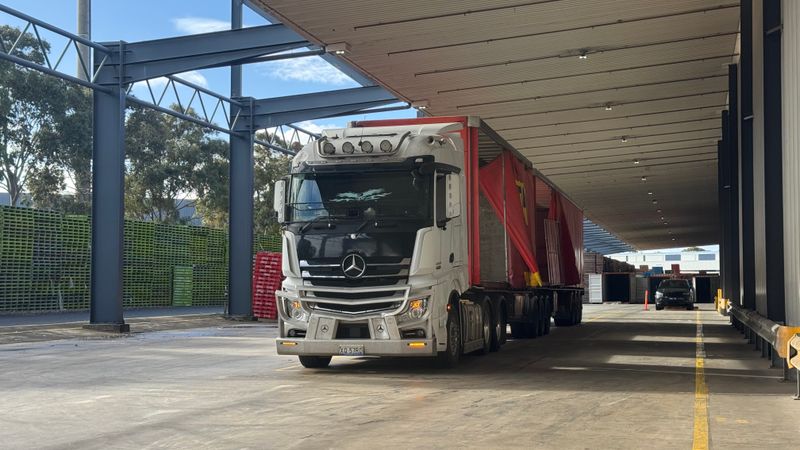 Large truck parked in a loading bay under a roof, ready for industrial transport.