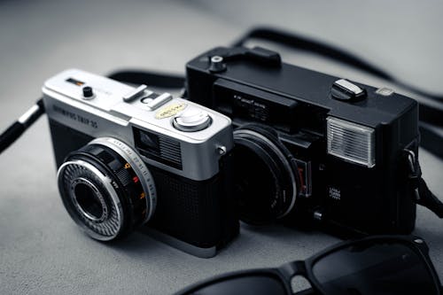 Free Black and Silver Camera on Gray Textile Stock Photo
