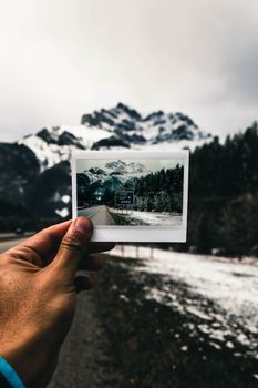 A picturesque scene of snow-capped mountains in Kananaskis, Alberta, Canada, framed through a handheld photo.