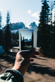 A Polaroid held against the backdrop of Kananaskis Mountains, Alberta, showcasing nature's beauty.