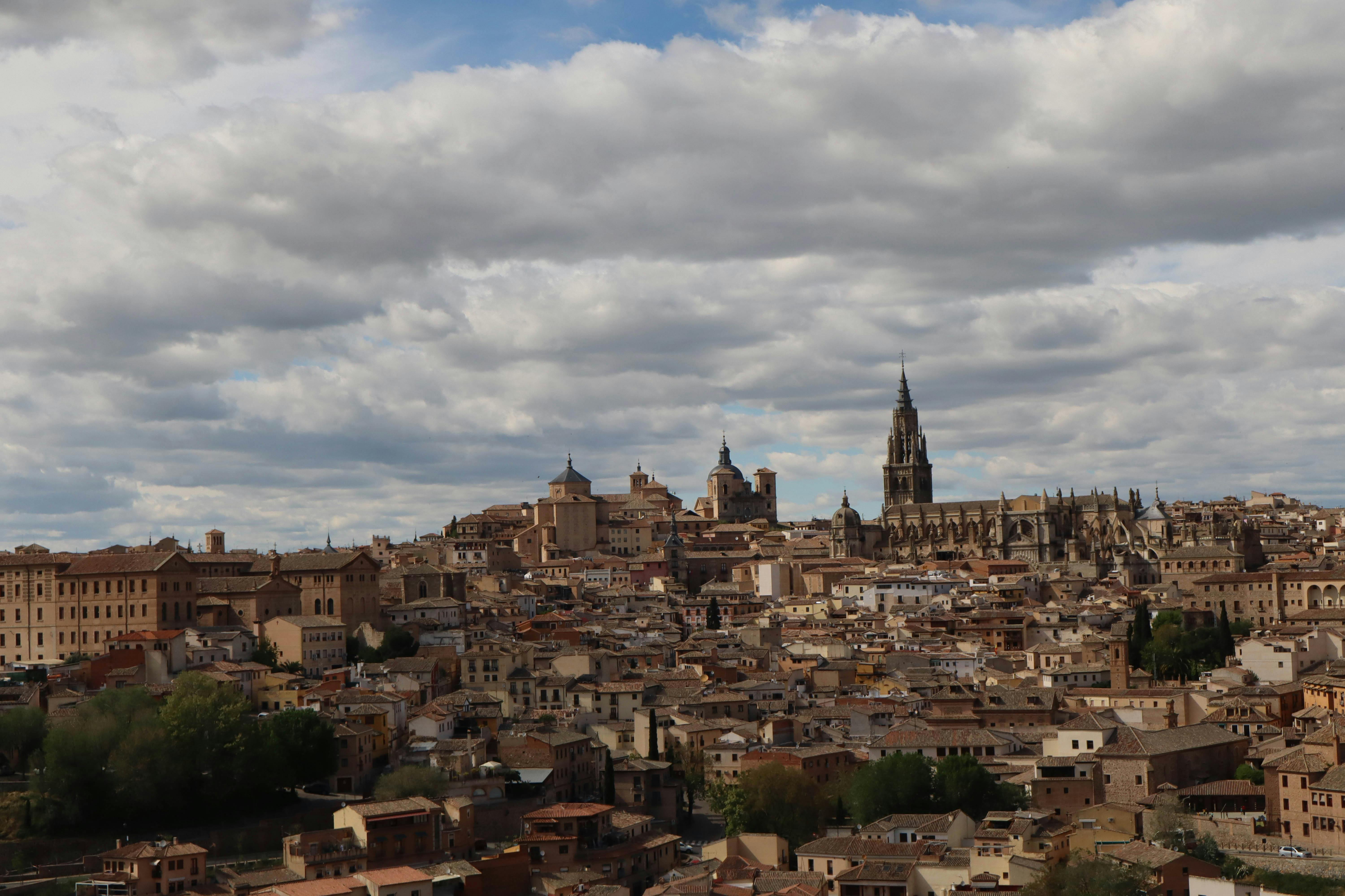 Panoramic view of Toledo, Spain with the iconic Toledo Cathedral under a cloudy sky.