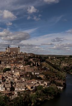Captivating aerial view of Toledo, Spain with its historic architecture and the Tagus River under a vibrant sky.