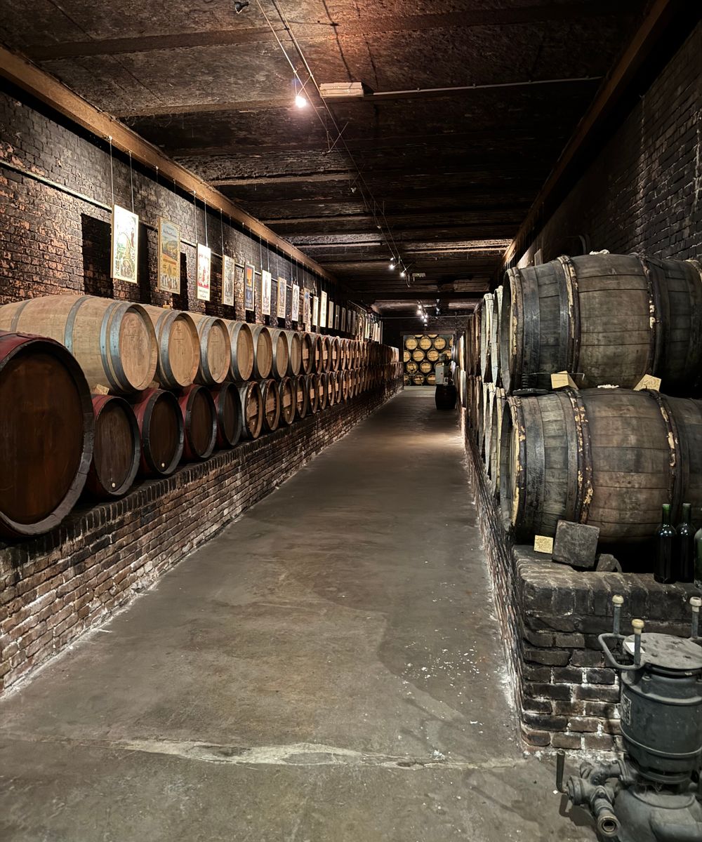 A brick cellar corridor with barrels stacked along one wall