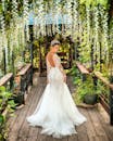 身着惊艳白色婚纱的新娘在郁郁葱葱的花园拱门上摆姿势