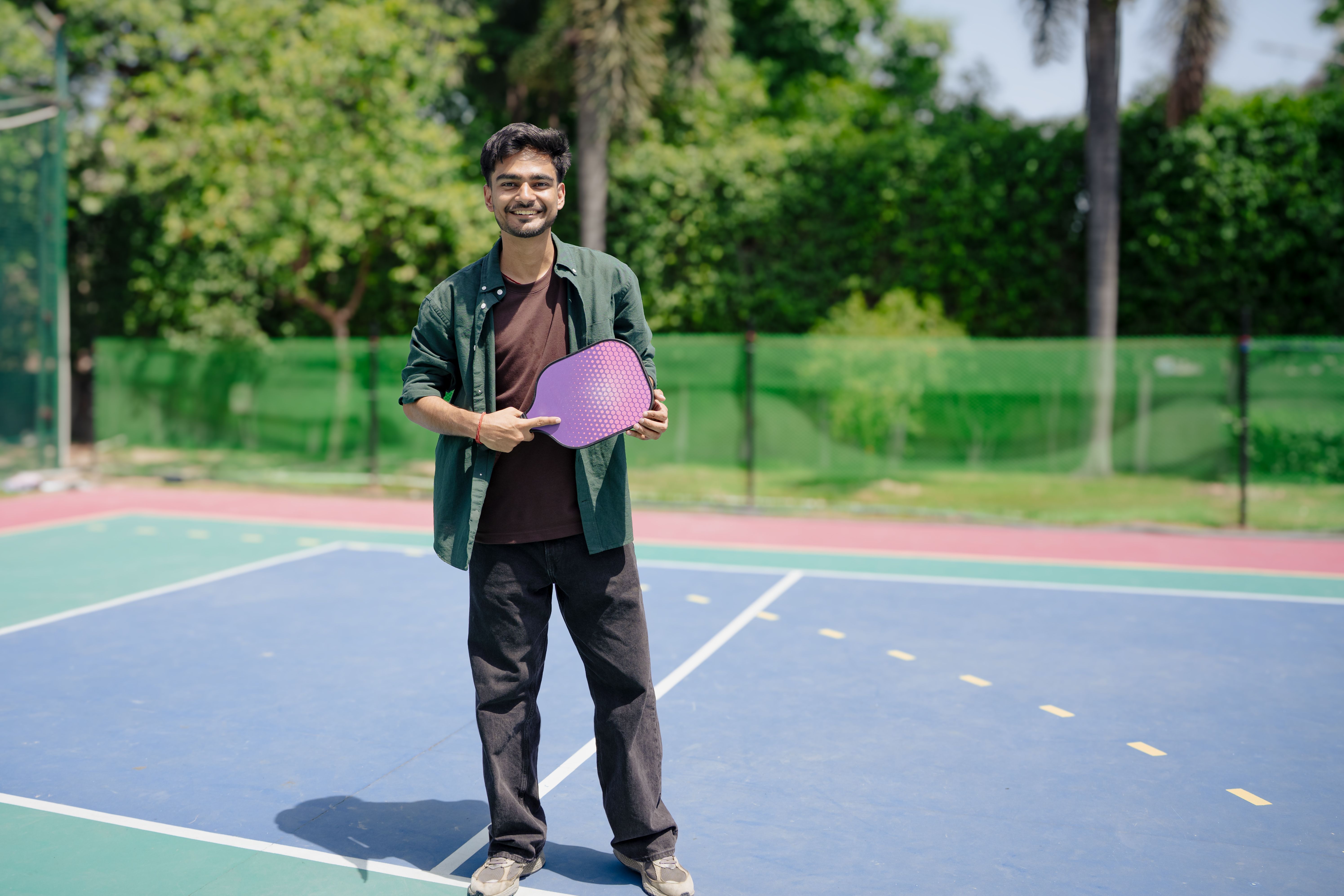 a person wearing a knee brace while holding a pickleball paddle, smiling