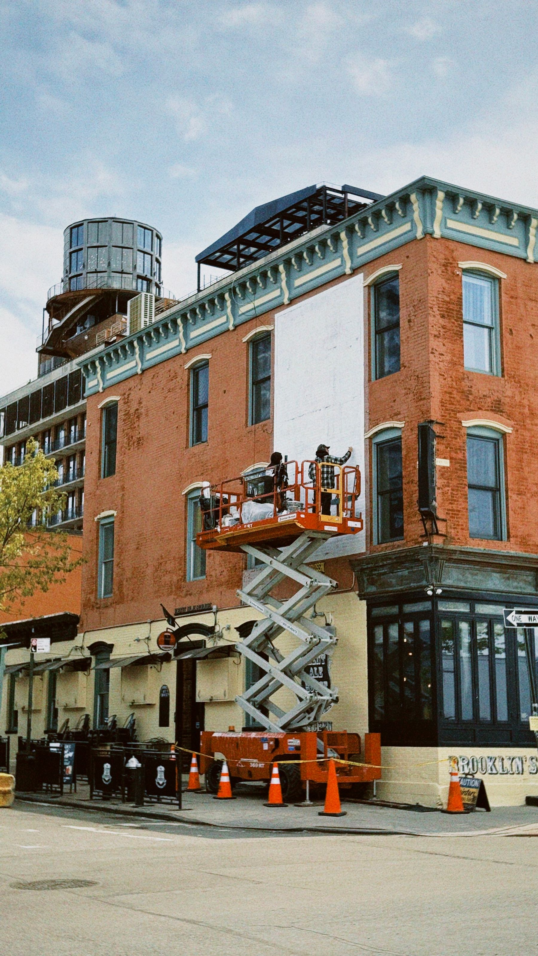 Scissor lift outside an older brick industrial building in Brooklyn, New York.