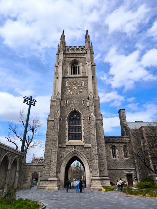 Free Gothic-style clock tower at Toronto University with blue sky and clouds. Stock Photo
