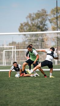Dynamic soccer practice with players engaging in intense midfield action outdoors.