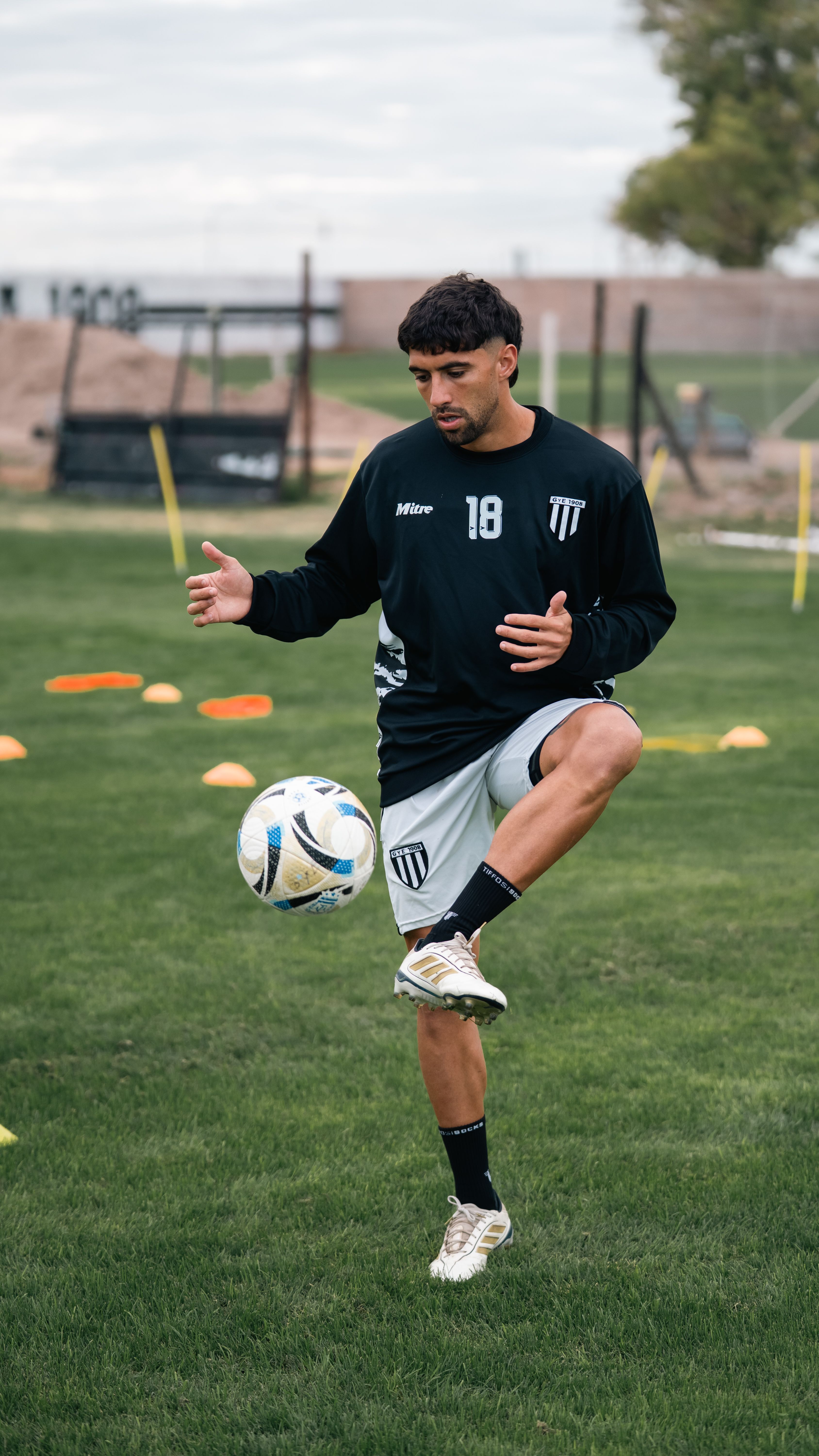 Young male soccer player practicing juggling skills on a grassy field during training.