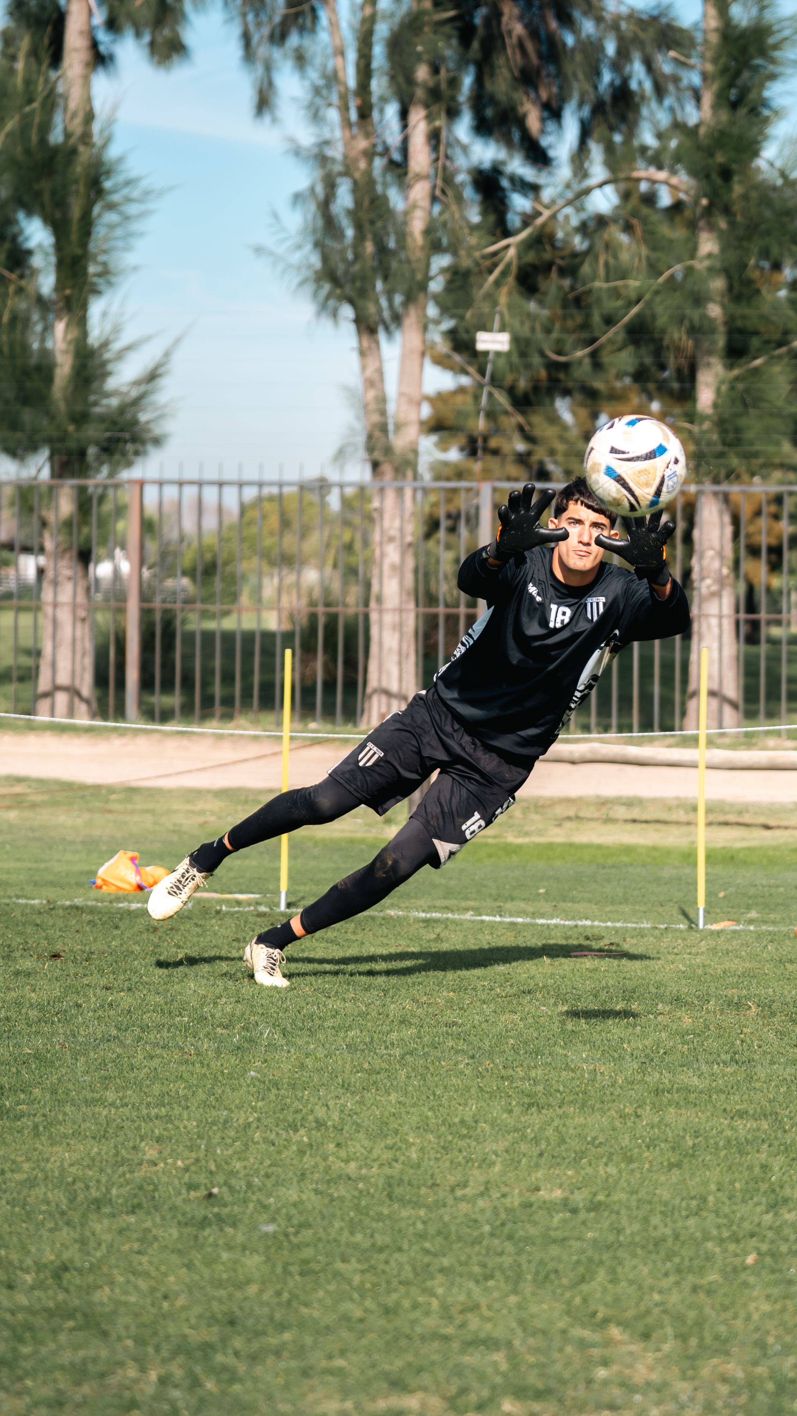 Goalkeeper making a dynamic save during soccer practice outdoors.