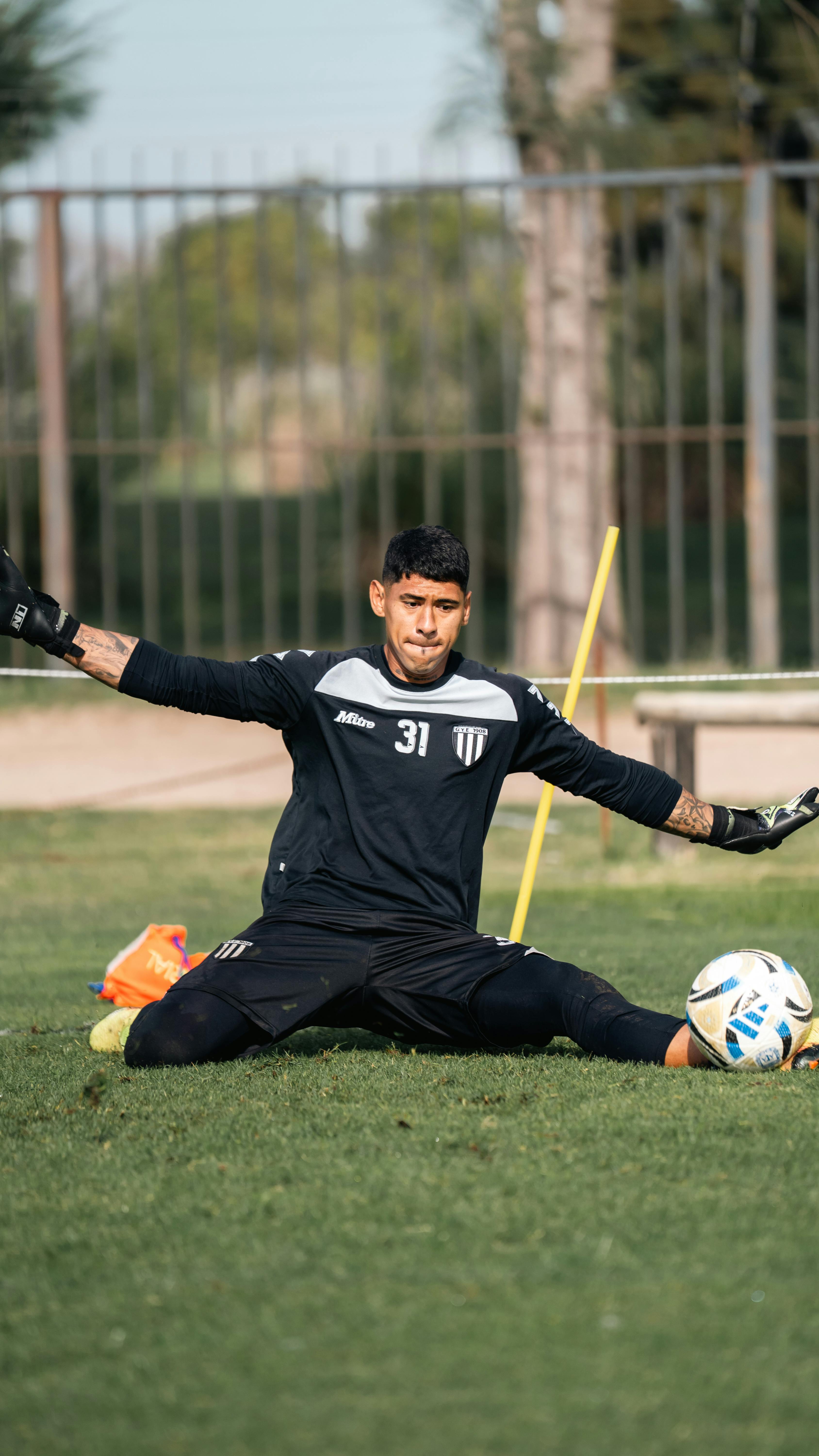 Goalkeeper practicing on a sunny day outdoors, showcasing sports training and determination.