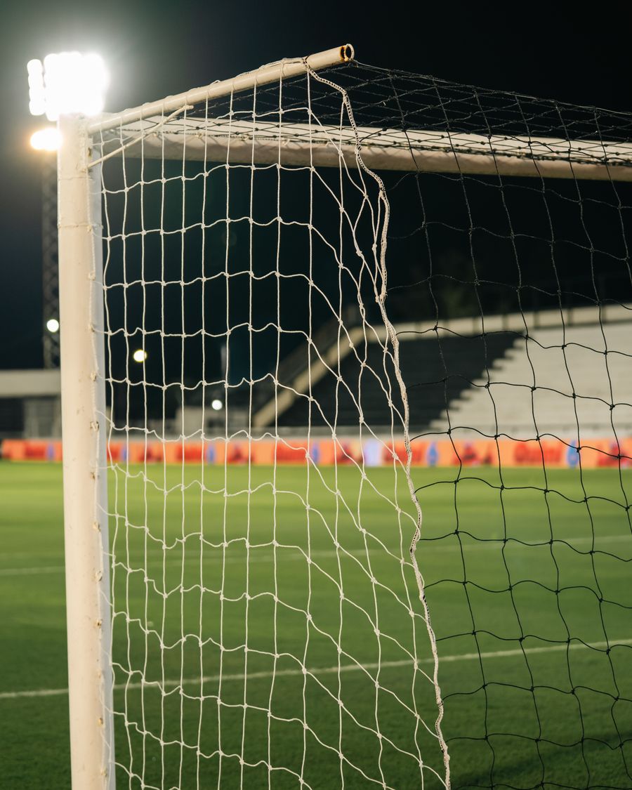 Floodlit goal net over an empty green pitch at night — photo by Franco Monsalvo on Pexels