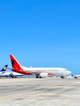 Commercial airplanes on the tarmac at Cape Town International Airport under a clear blue sky.
