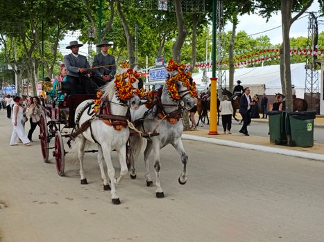 A vibrant horse carriage parade during a festive fair in El Puerto de Santa María, Spain.