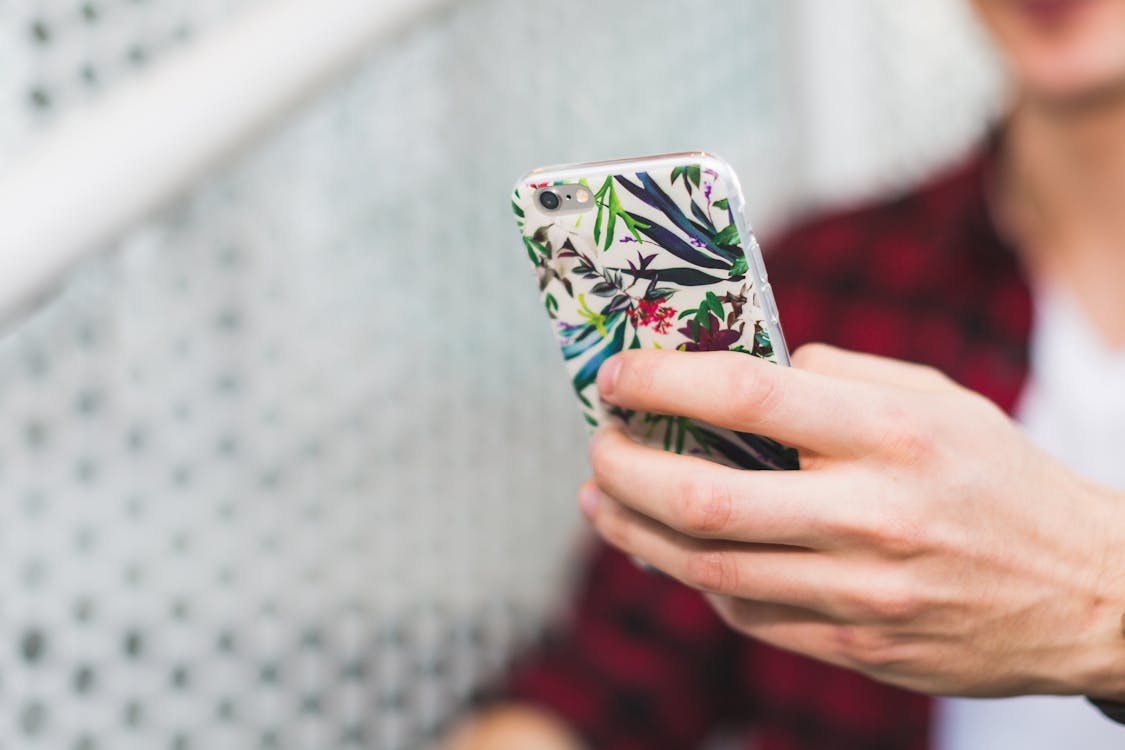 Free Person Holding Smartphone With White and Green Floral Case Stock Photo