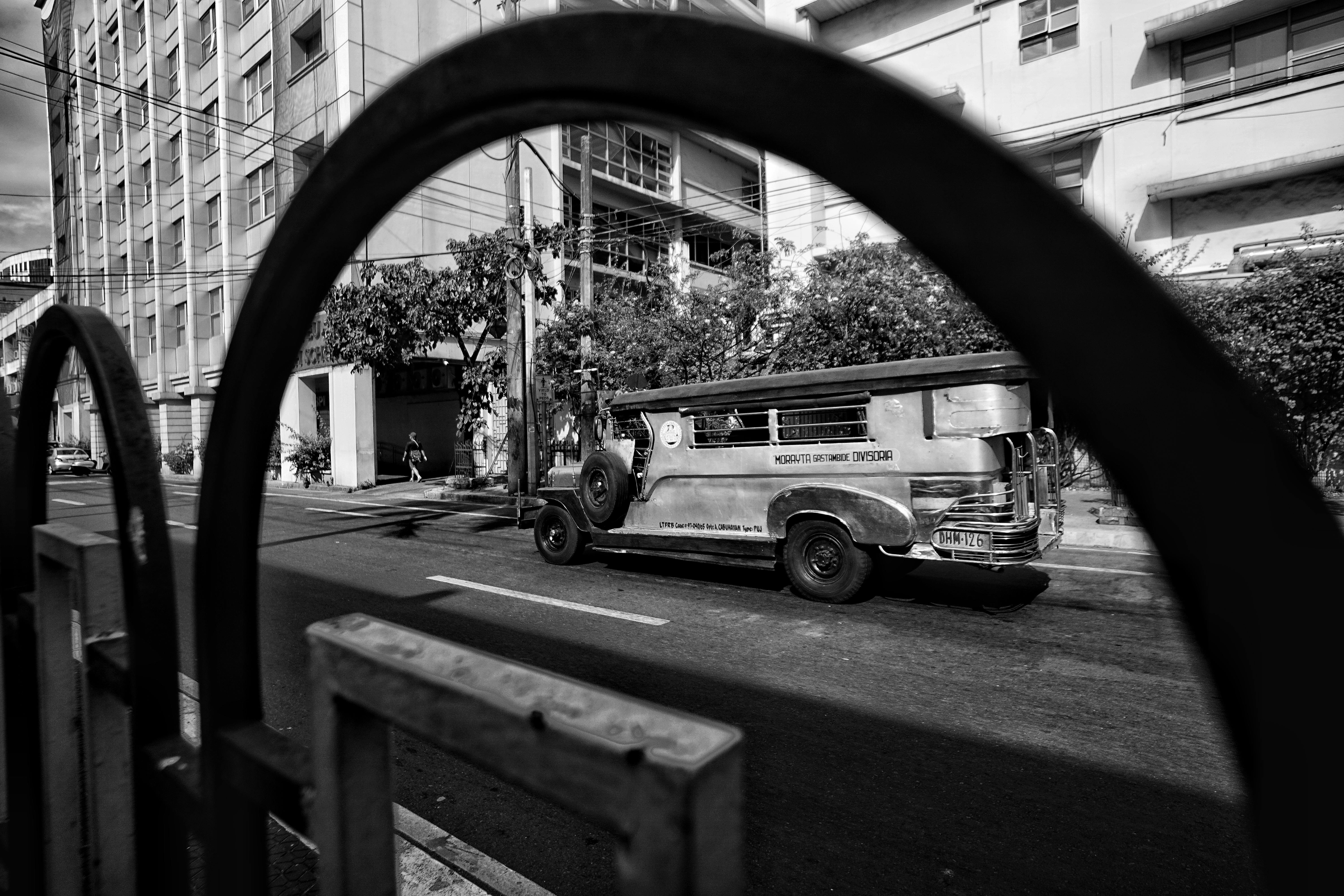 Monochrome city scene featuring a traditional jeepney parked on an urban street.