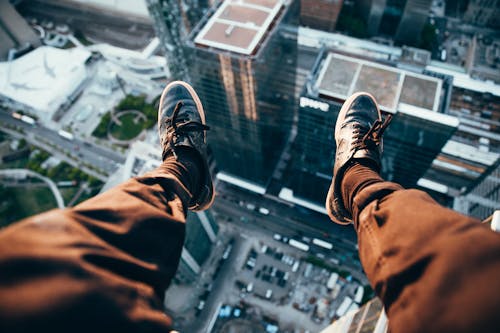 Person Showing Black Shoes While on Building