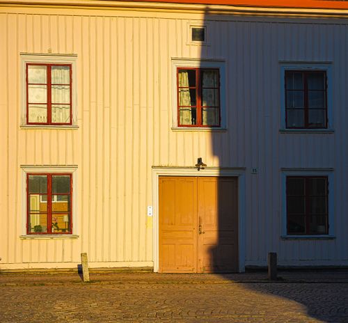 Free Sunlit wooden facade of a vintage Scandinavian house with red-framed windows. Stock Photo