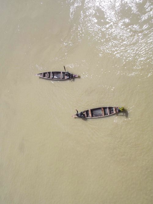 Free Aerial view of two fishermen rowing wooden boats on calm waters, showcasing traditional fishing methods. Stock Photo