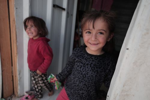 Free Two young girls smiling brightly while standing in a doorway, conveying joy and friendship. Stock Photo