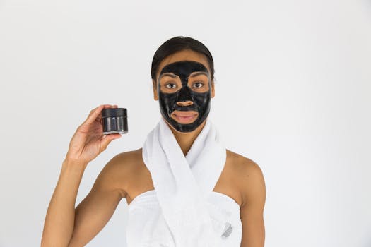 A young woman applies a charcoal face mask promoting skincare and beauty routines.