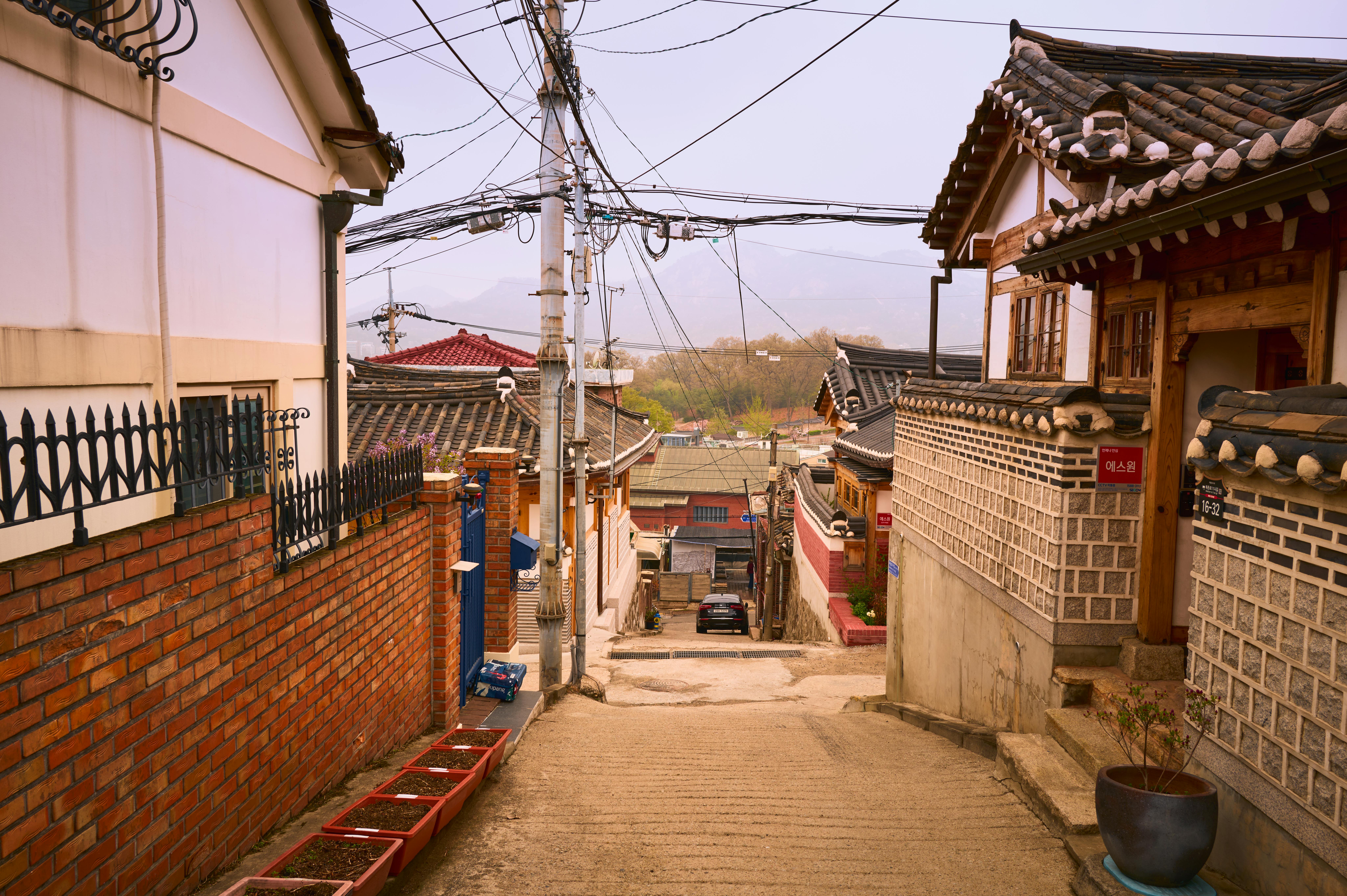 Narrow Seochon hanok alley with grey tile rooves and late afternoon side light