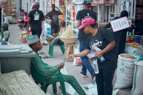 Free Woman distributing promotional material at lively outdoor market scene. Stock Photo