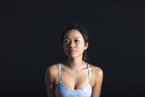Free A serene portrait of a woman in a sports bra against a dark studio backdrop. Stock Photo