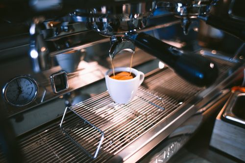 Free Close-up view of espresso being brewed into a cup using a professional coffee machine in a café. Stock Photo