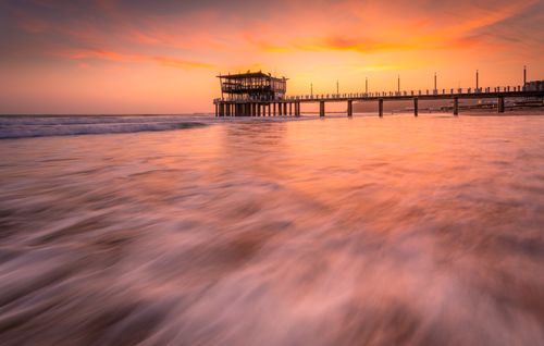 Free Capture of a beautiful sunset over the ocean with Durban's pier, showcasing vibrant colors and waves. Stock Photo