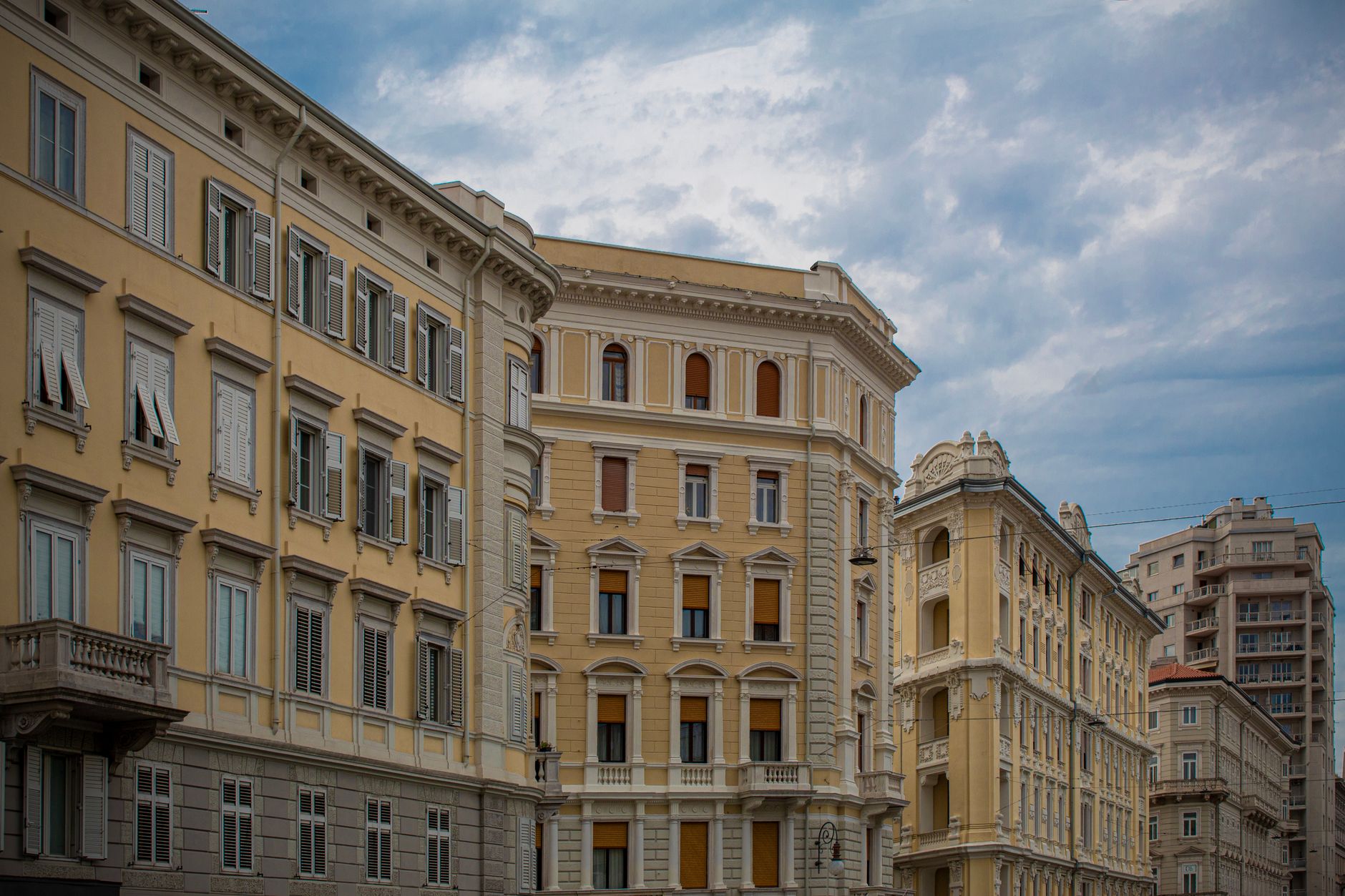Classic architecture of historic buildings in Trieste, Italy under a cloudy sky.