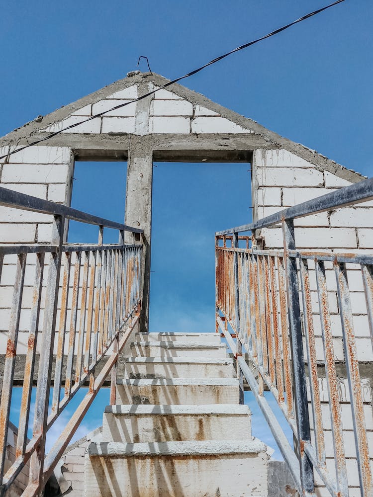 Half Ruined Old House With Cement Stairs Under Blue Sky