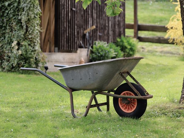 Wheelbarrow and garden equipment in a green garden