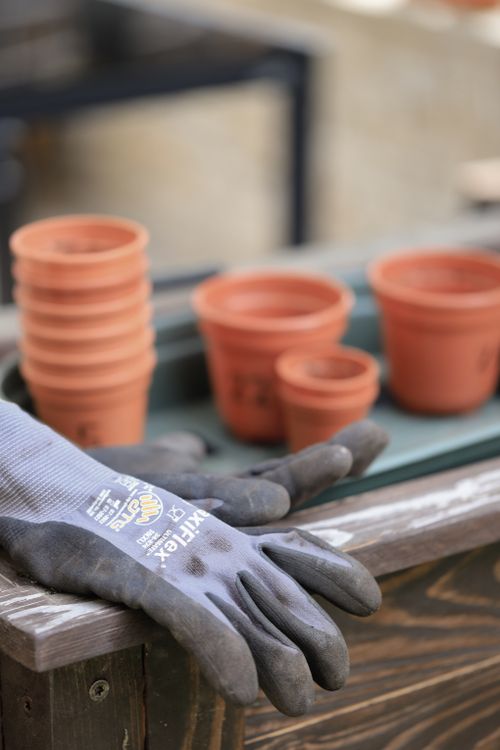 Free Stacked clay pots and gardening gloves on a wooden table, ready for planting. Stock Photo