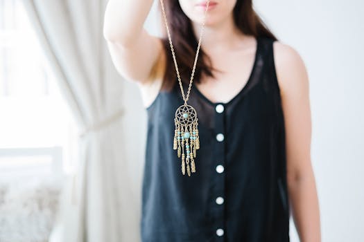 Stylish woman posing with a bohemian dreamcatcher necklace in a bright room.