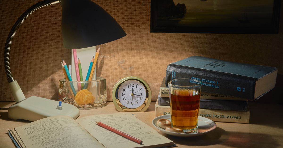 A tranquil desk setup with books, tea, and a lamp, ideal for studying.