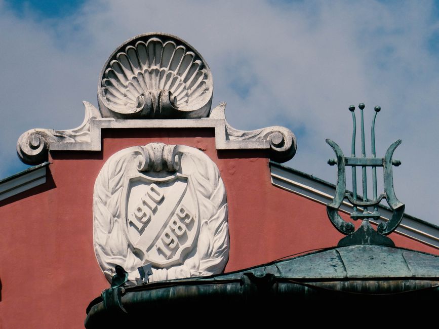 Close-up of historic European architecture with decorative relief and dates 1910 and 1999.